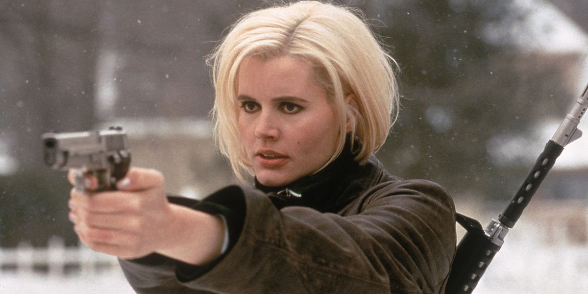 Geena Davis with blonde hair holding a gun.