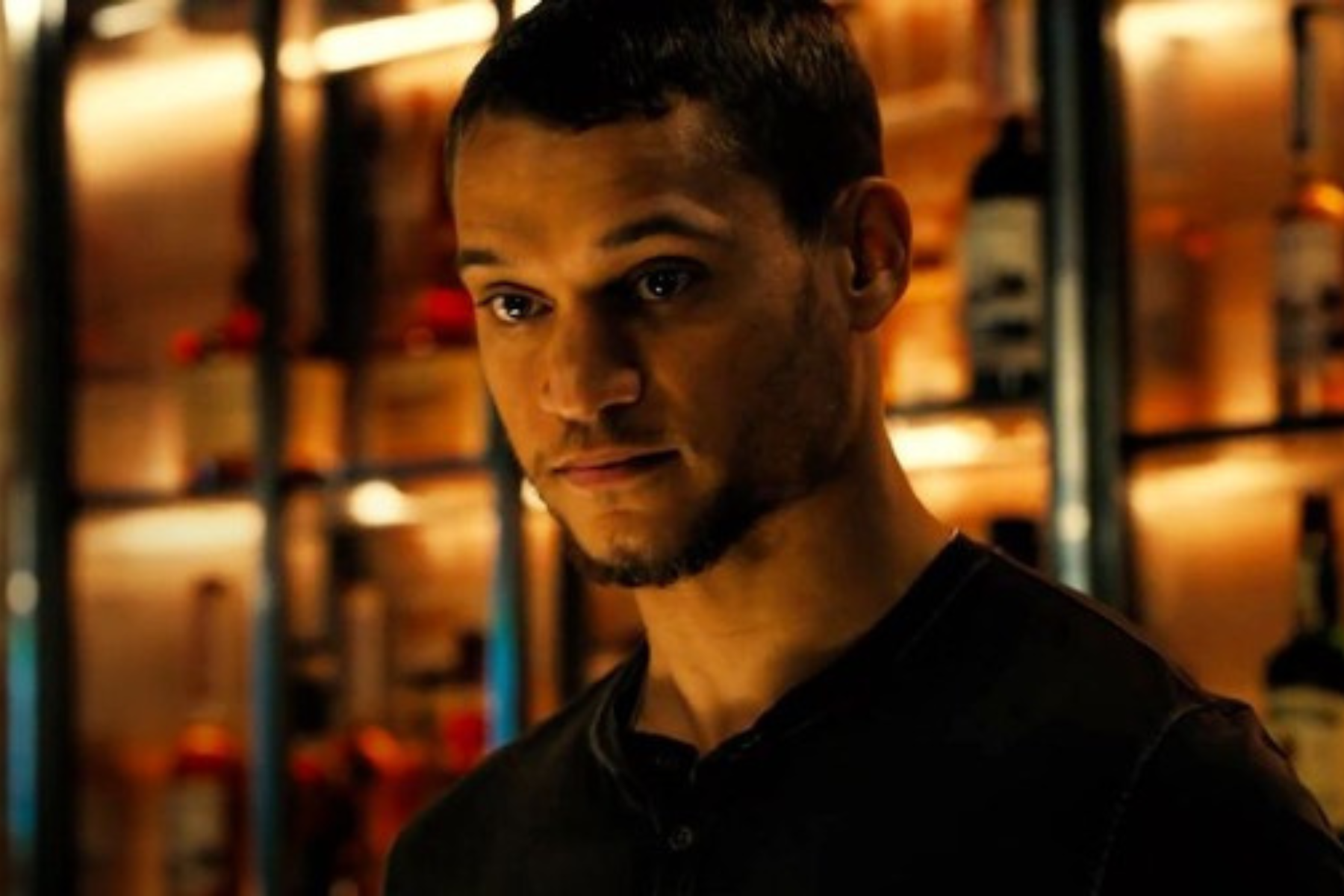 Tyriq Withers as Ledger Ward looks forward with a serious expression in warm lighting