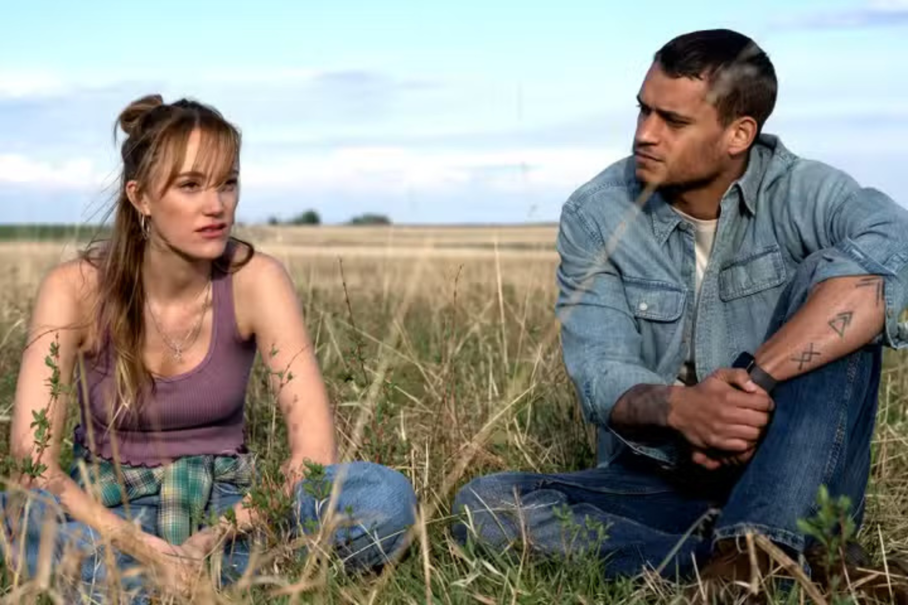 Maika Monroe as Kenna Rowan and Tyriq Withers as Ledger Ward sit in a field having a serious conversation