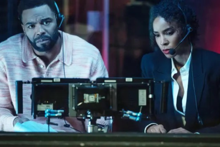 Relationship Goals Review: A Charming Rom-Com With a Soundtrack Worth Saving wo characters wearing headsets work behind the scenes at a TV broadcast in Relationship Goals