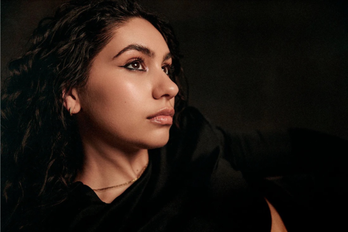 Side profile of Alessia Cara in soft lighting against a dark background