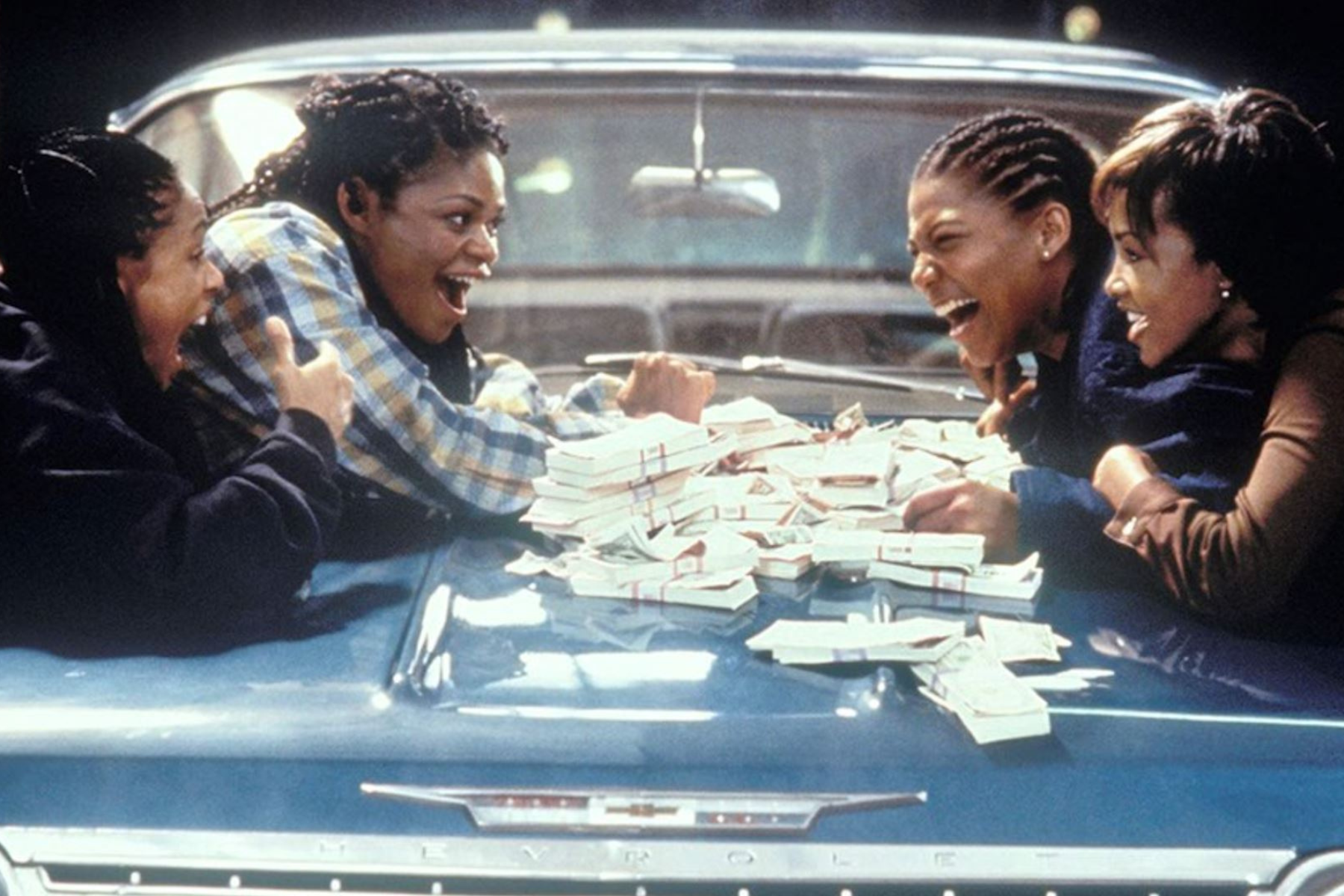Queen Latifah as Cleo Sims laughing with friends over stacks of money in Set It Off