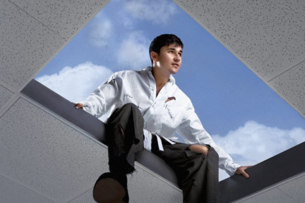 John Summit sits in an open ceiling panel looking up at the sky, symbolizing escape and transition