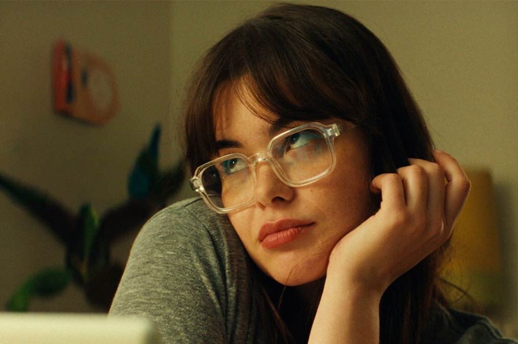 Mile End Kicks Review: Barbie Ferreira is a True Movie Star in a Finely Made Coming-of-Age Story Mile End Kicks film still - Young woman with clear-framed glasses resting her chin on her hand, gazing pensively to the side.
