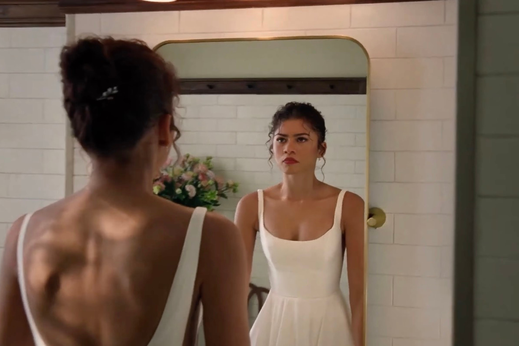 Zendaya as Emma in The Drama (Photo courtesy of A24). Zendaya as Emma stands in front of a mirror wearing a white dress, looking serious and introspective