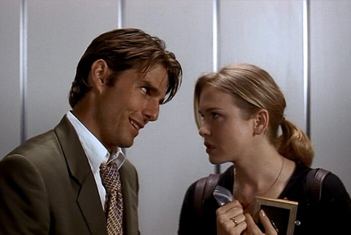 Jerry Maguire 30th Anniversary Review: Tom Cruise’s Most Heartfelt Work Still Holds Up Tom Cruise and Renee Zellweger in Jerry Maguire. Man in a suit leans close to a woman in an elevator, both looking at each other; she holds a notebook and folder and appears surprised.