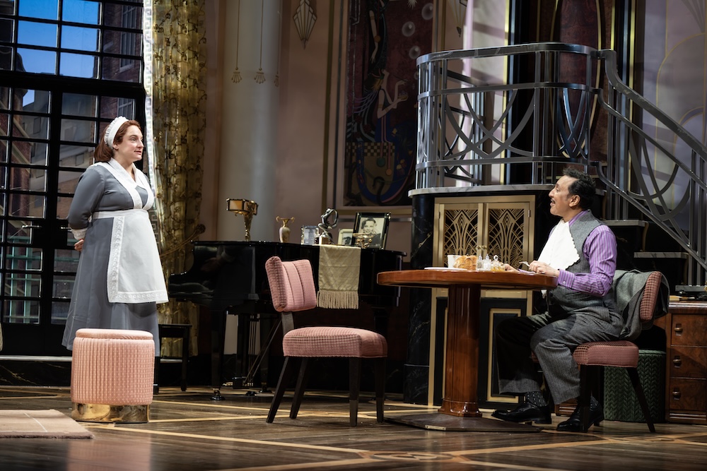 Fallen Angels on Broadway Review: These Angels Fly Away with Big Laughs Theatrical scene: a maid in a gray dress and white apron stands and speaks to a man seated at a round wooden table on a stage.