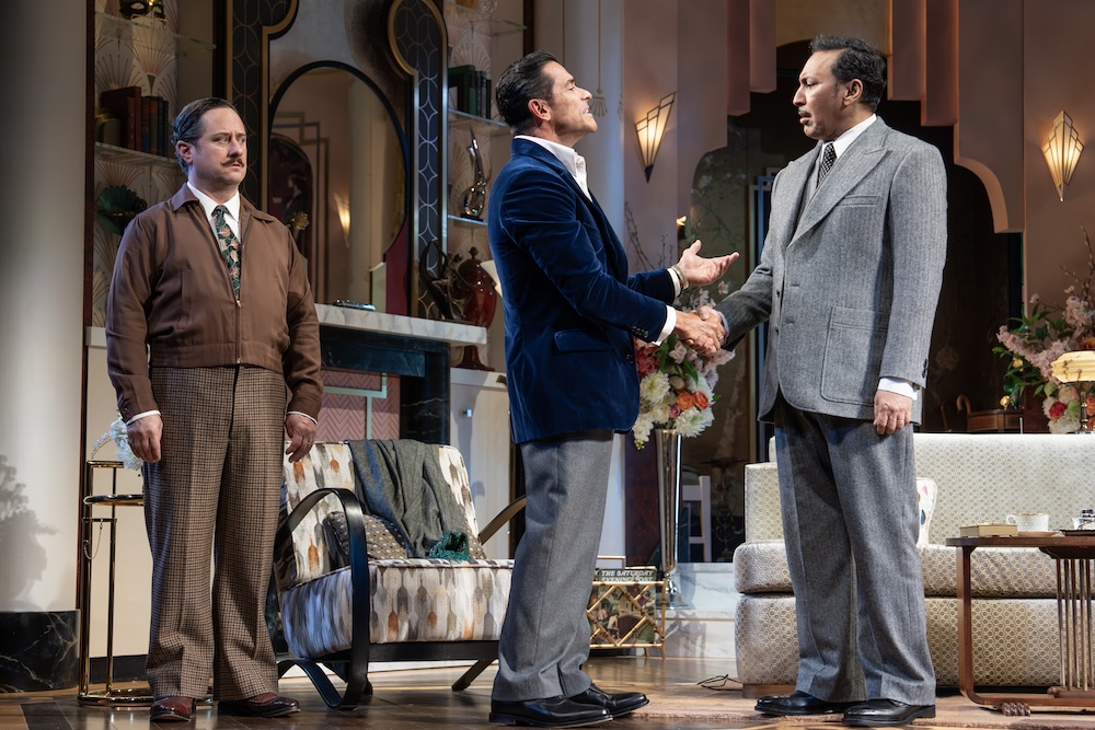 Fallen Angels on Broadway Review: These Angels Fly Away with Big Laughs Two men on a stage shake hands in a formal setting while a third man watches, mid-20th-century decor in the background.