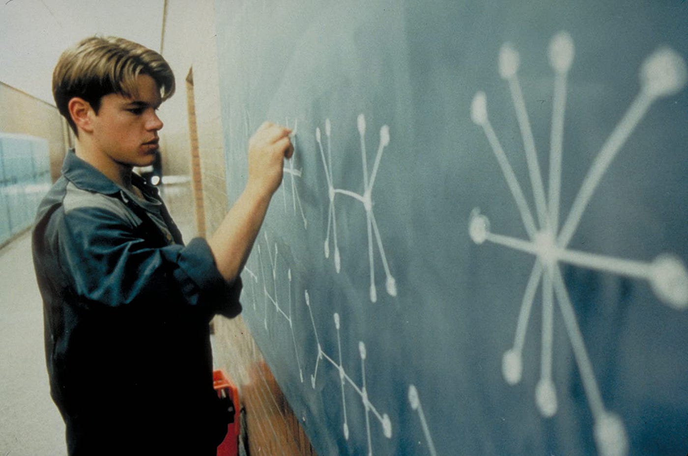 The 12 Best Movies Featuring Matt Damon in a Principal Role Young man in a hallway draws chalk diagrams of molecular structures on a blue wall.