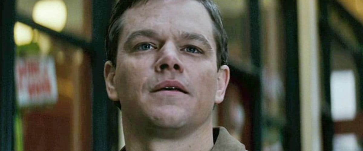 The 12 Best Movies Featuring Matt Damon in a Principal Role Close-up of a man with short brown hair looking slightly upward in a dim indoor setting.