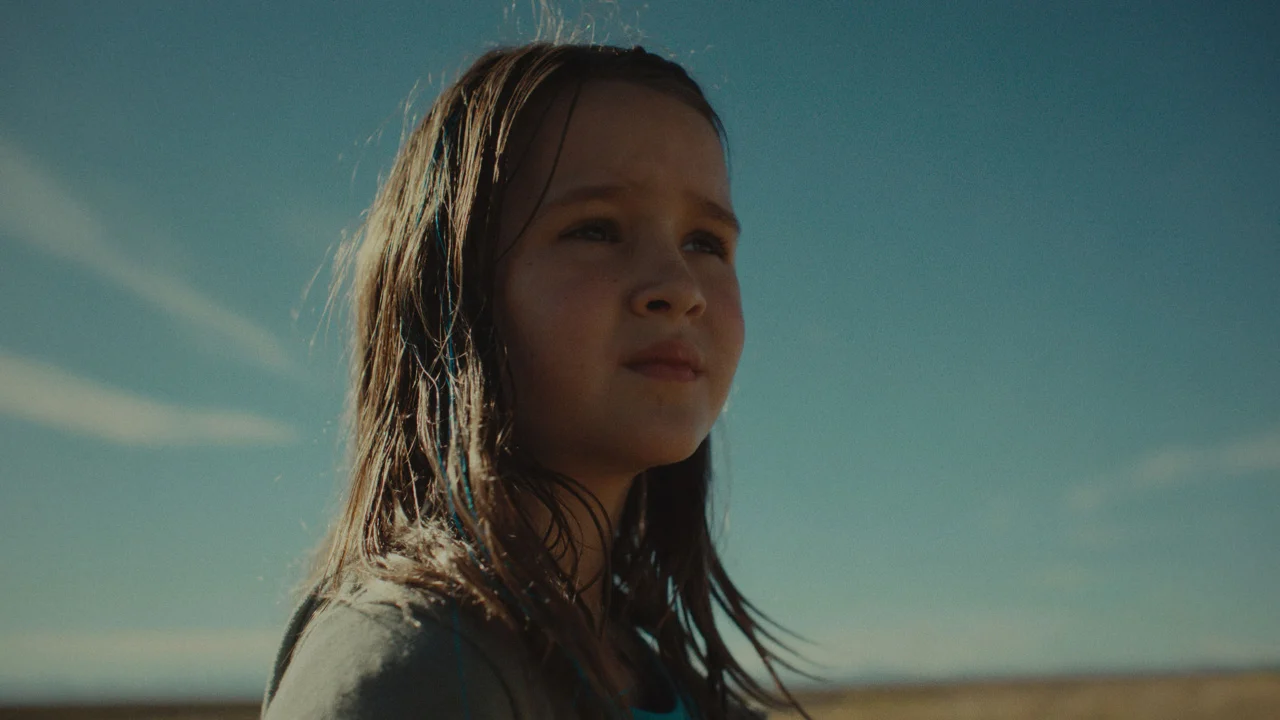 Omaha Review: John Magaro is Amazing in a Dramatic Film That Packs a Wallop Young girl with wet hair standing in a wide desert under a clear blue sky, gazing into the distance.