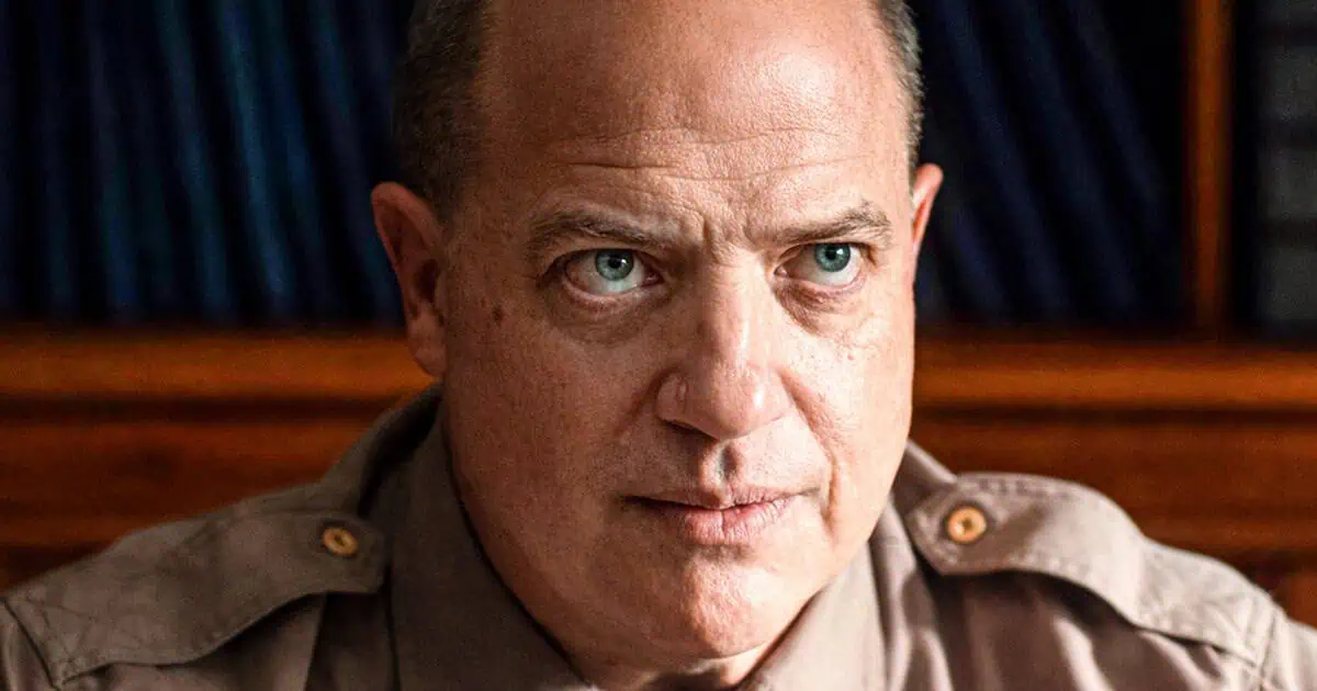 Pressure Review: Brendan Fraser and Andrew Scott are in Top Form for Powerful WWII Drama Close-up of a middle-aged man with blue-green eyes looking to the side, wearing a khaki shirt, shelves in the background.