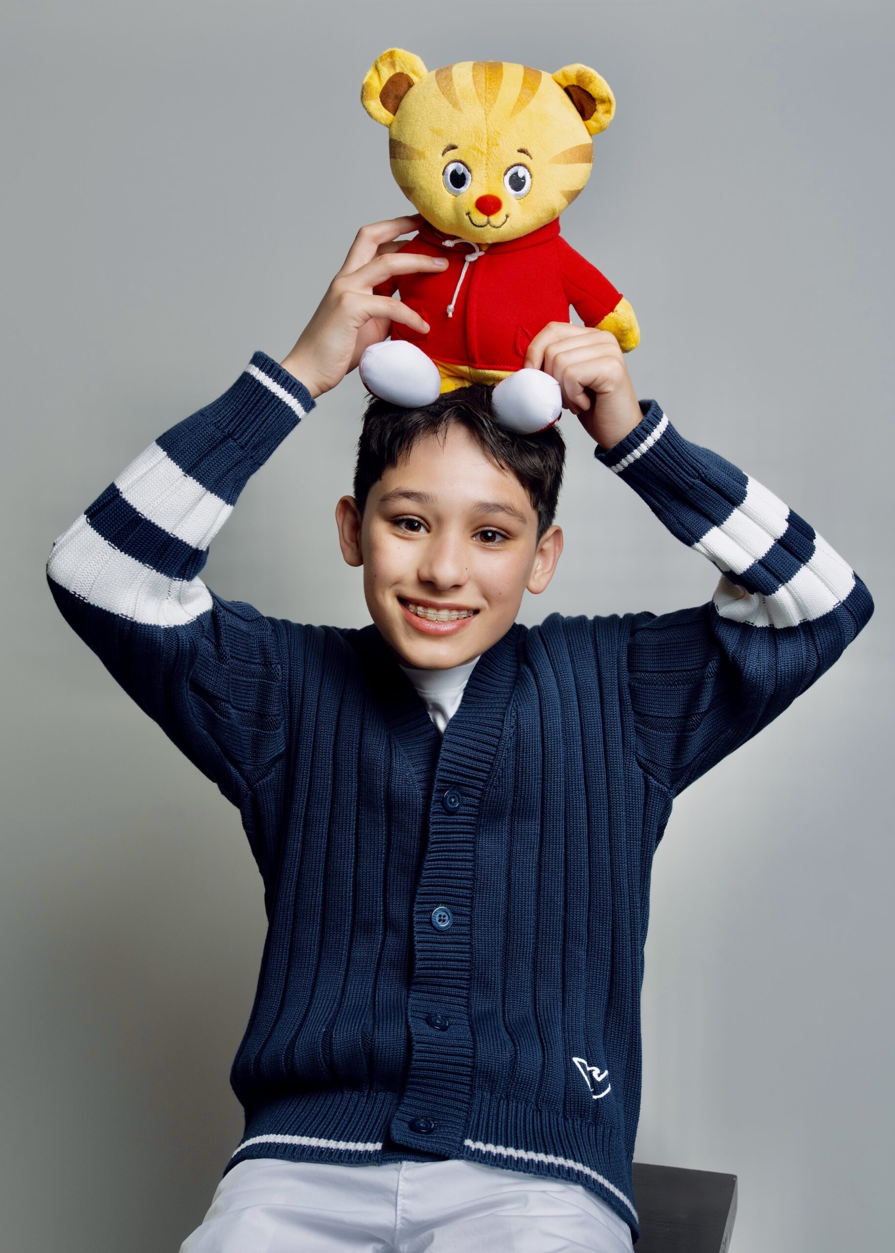 Rain Janjua on Voicing Chase in PAW Patrol: The Dino Movie Actor Rain Janjua smiles while posing for a headshot photo with a stuffed animal on top of his head.