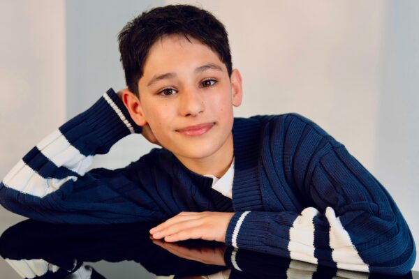 Actor Rain Janjua poses for a headshot photo while facing forward, smiling for the camera.