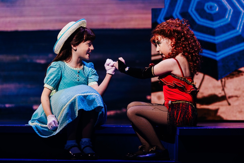 Beaches: A New Musical Review: A Beautiful Tale of Friendship Told in a Heartwarming Fashion Two young performers in vintage costumes greet with a fist bump on stage during a show.