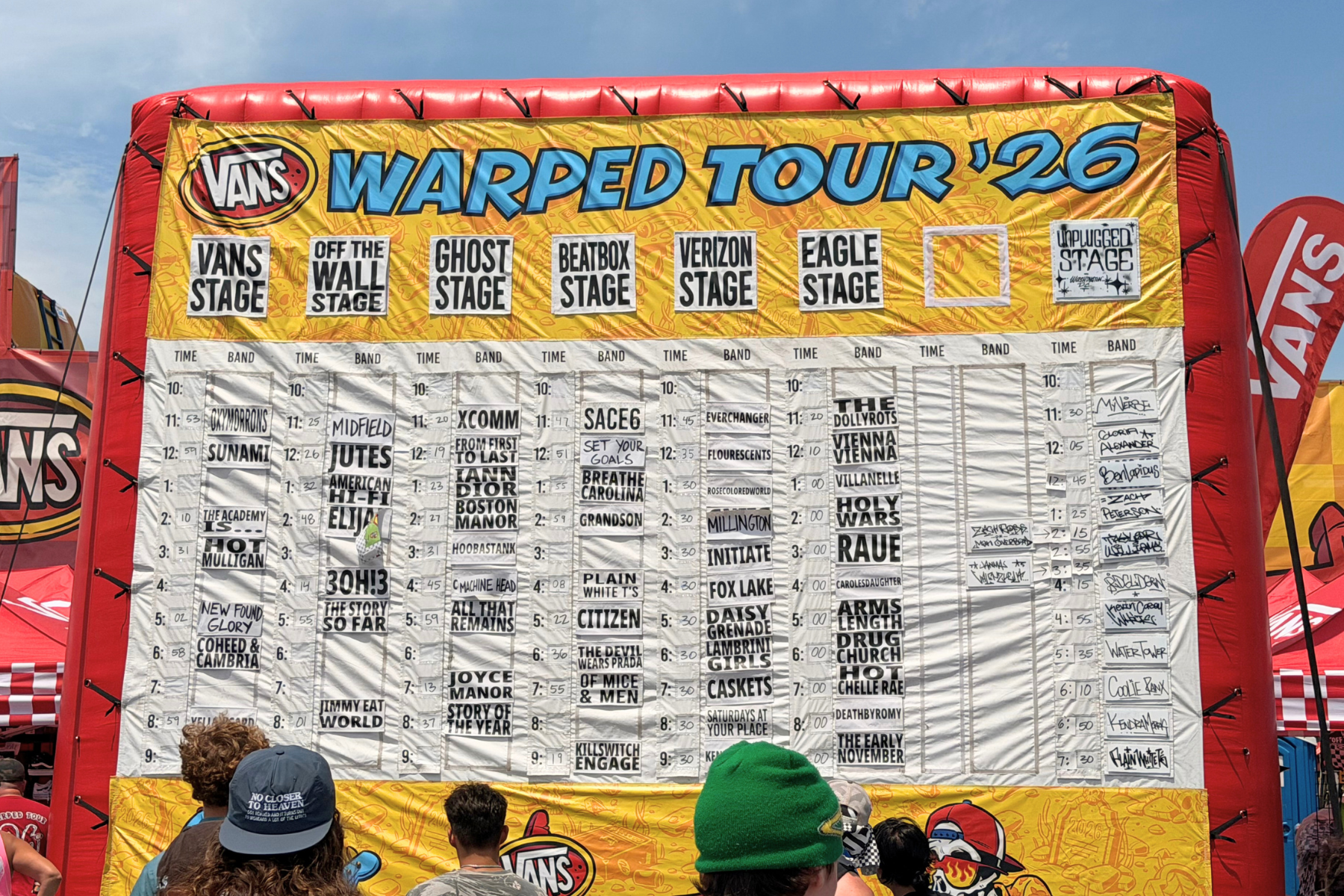 Vans Warped Tour Day Two Schedule - Eulalie Magazine Vans Warped Tour D.C. Review: The Punk Rock Summer is Back Large yellow Vans Warped Tour '26 schedule board showing stage names and time slots, mounted on a red inflatable structure.