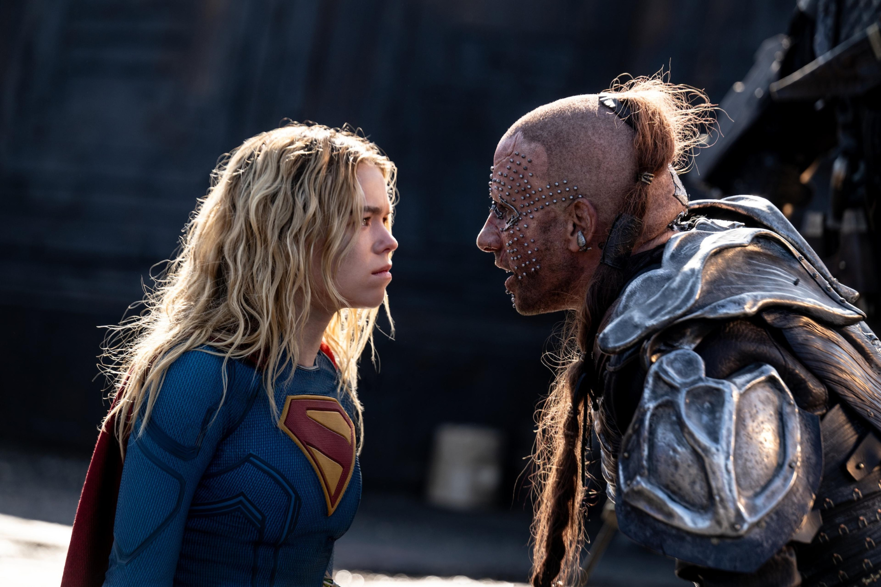 Supergirl Review: Strong Performances Can’t Save an Uneven Adventure Supergirl in blue armor faces a studded, heavily armored foe in a tense standoff.