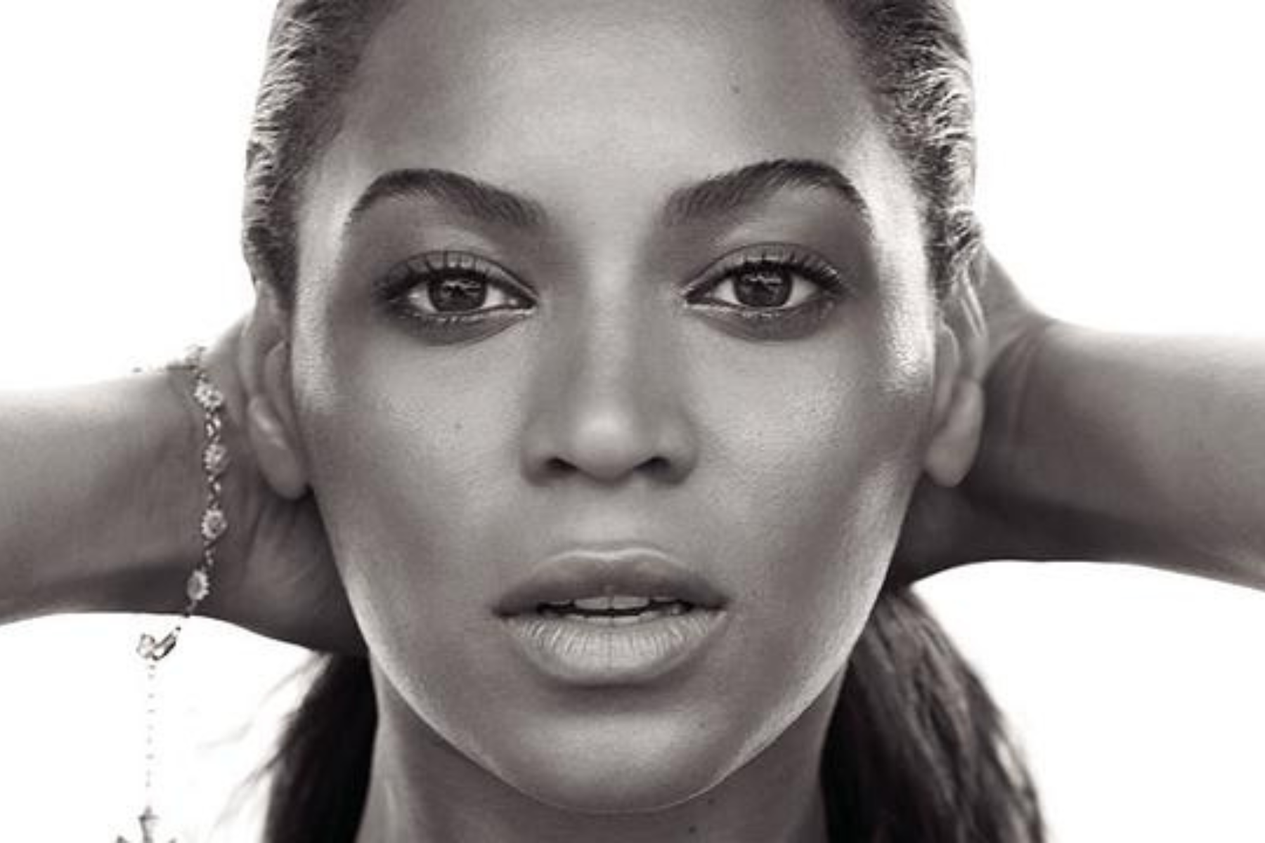 Every Beyoncé Album – Ranked! Close-up portrait of a young woman with hands behind her head, looking at the camera (black-and-white).