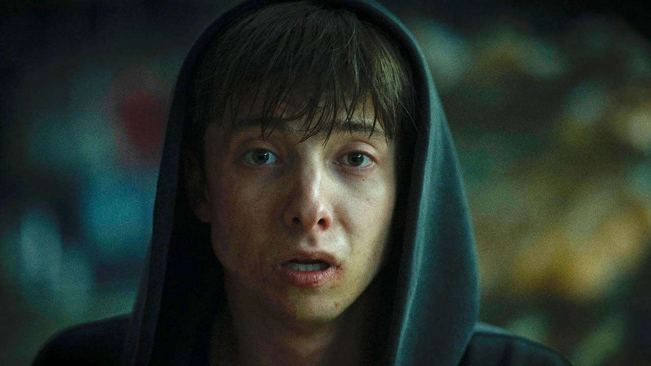 Leviticus Review: A Frightening Horror Movie That Has a Lot on Its Mind Young person in a dark hoodie with a pale face and bruised lip, looking distressed.