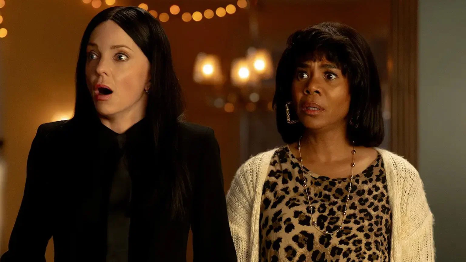 scary movie - Eulalie Magazine Scary Movie 6 Review: Only a Few Zany Scenes Hit the Comic Bullseye in This Wild Sequel Two surprised women stand indoors, faces showing shock—one with long black hair in a black outfit, the other in a leopard print top and cream cardigan.