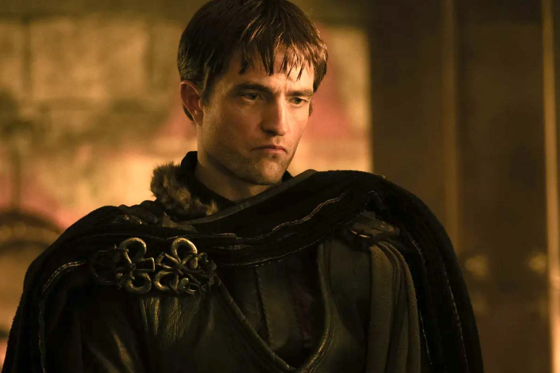 The Odyssey Review: Christopher Nolan Delivers a Modern Masterpiece Knight in dark fur-trimmed cloak looking to the side in a moody, warm-lit setting