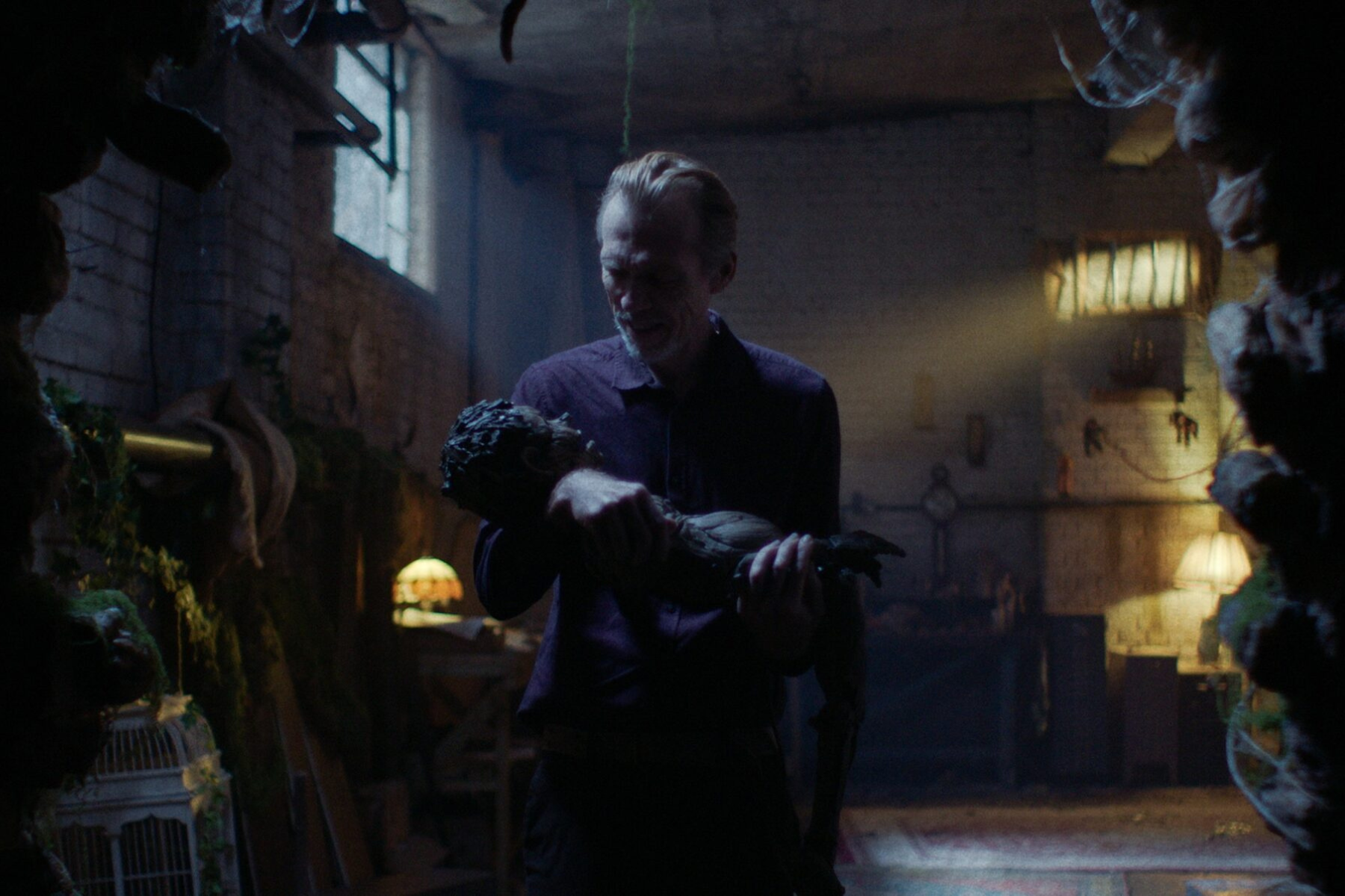 Pinocchio: Unstrung Preview: Release Date, Cast, Plot, and More Man in a purple shirt holds a large, lifelike creature-like figure in a dimly lit alley.