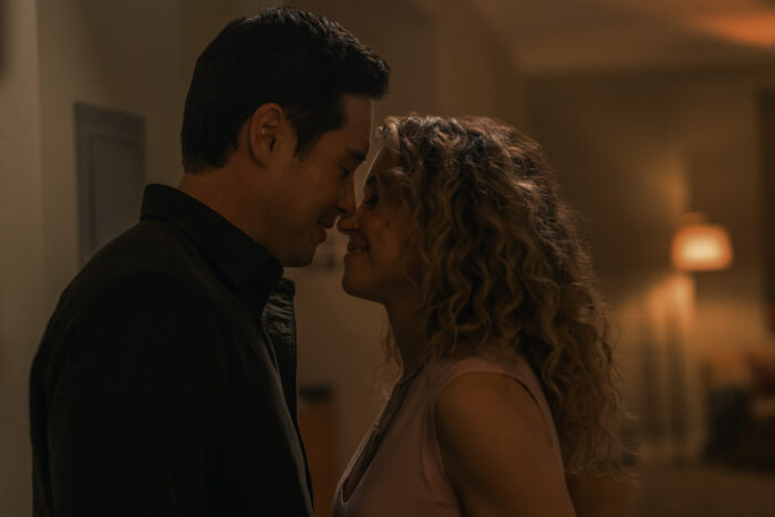 Maximum Pleasure Guaranteed Season 1 Episode 10 Review: Queens Couple leaning in for a kiss in a dimly lit hallway, faces close together.