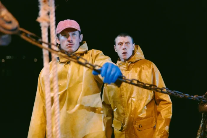 Rose of Nevada Review: A Slow-Burn Movie That Sneaks Up on You and Hits Hard Two sailors in yellow raincoats onboard a ship at night, gripping a heavy chain.