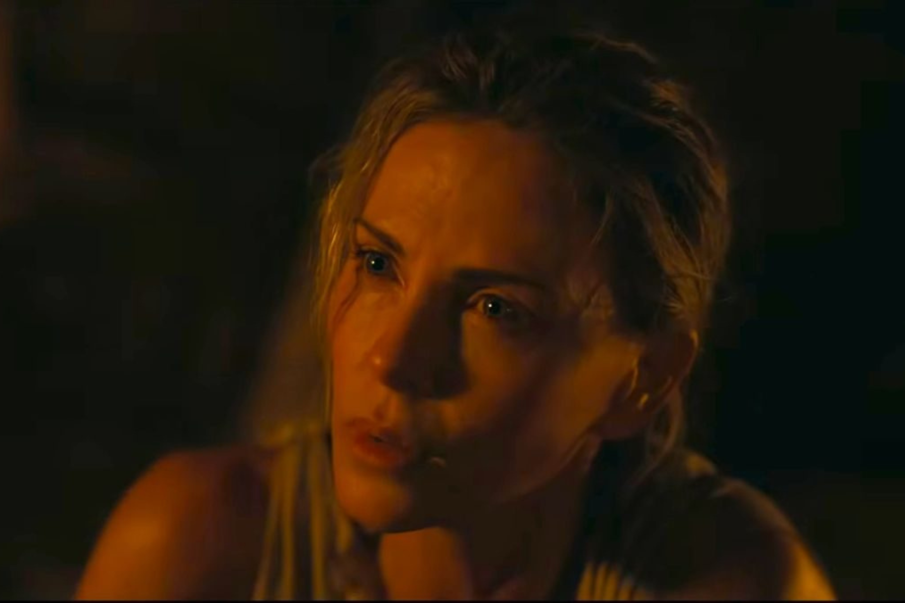 The Odyssey Review: Christopher Nolan Delivers a Modern Masterpiece Close-up of a woman in orange firelight, eyes wide with worry in a dark setting.