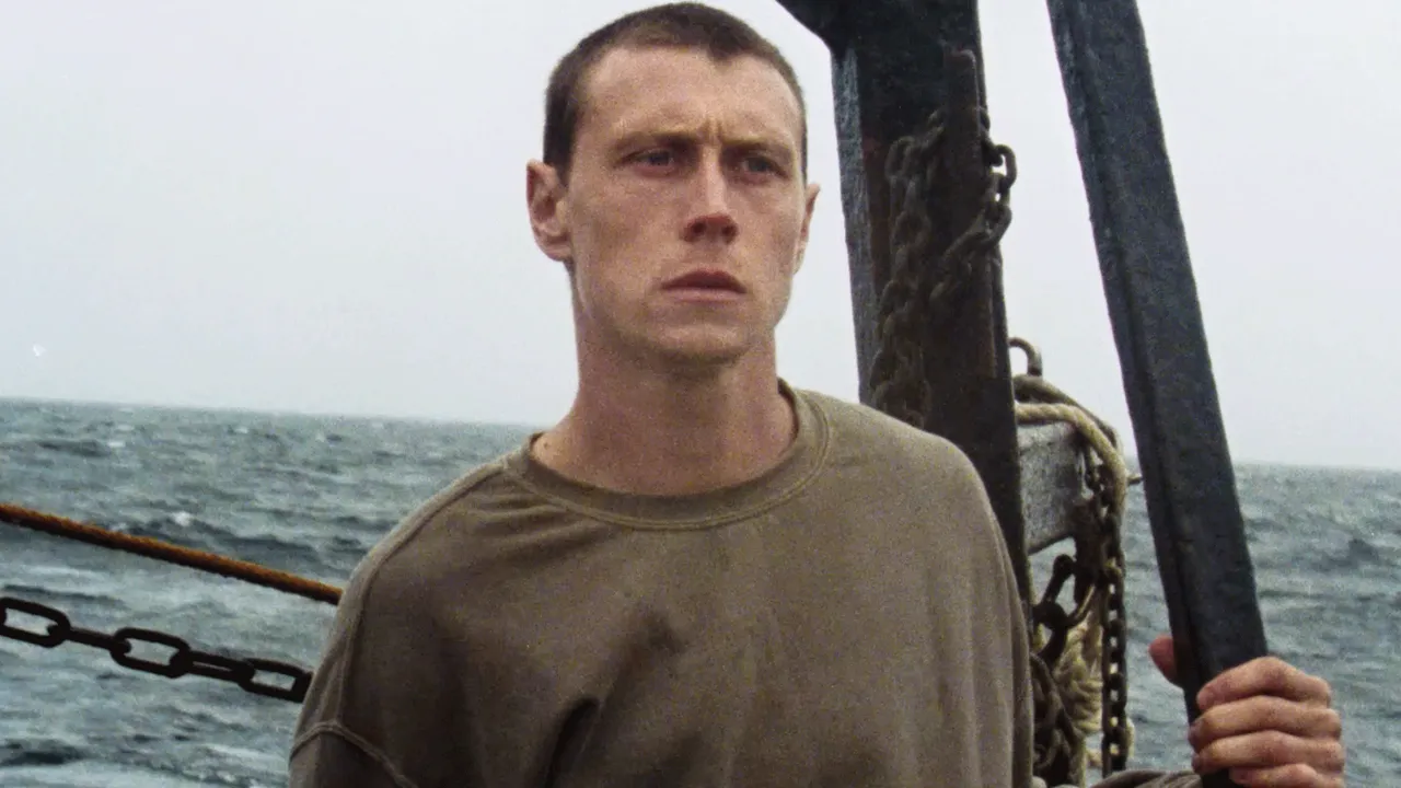 roseofnevada-4 - Eulalie Magazine Rose of Nevada Review: A Slow-Burn Movie That Sneaks Up on You and Hits Hard Man on a boat at sea, gripping a vertical post, looking toward the horizon.