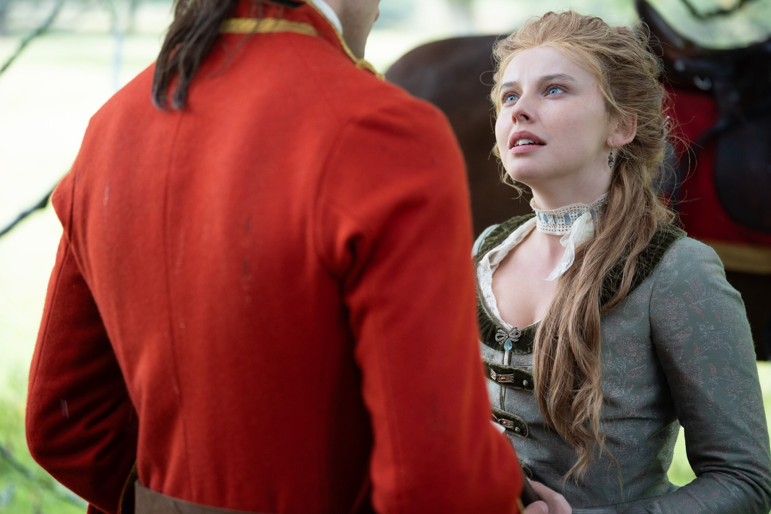 Young Washington Preview: Release Date, Cast, Plot, and More Woman in a historical green gown with lace collar gazes up at a man in a red coat outdoors.