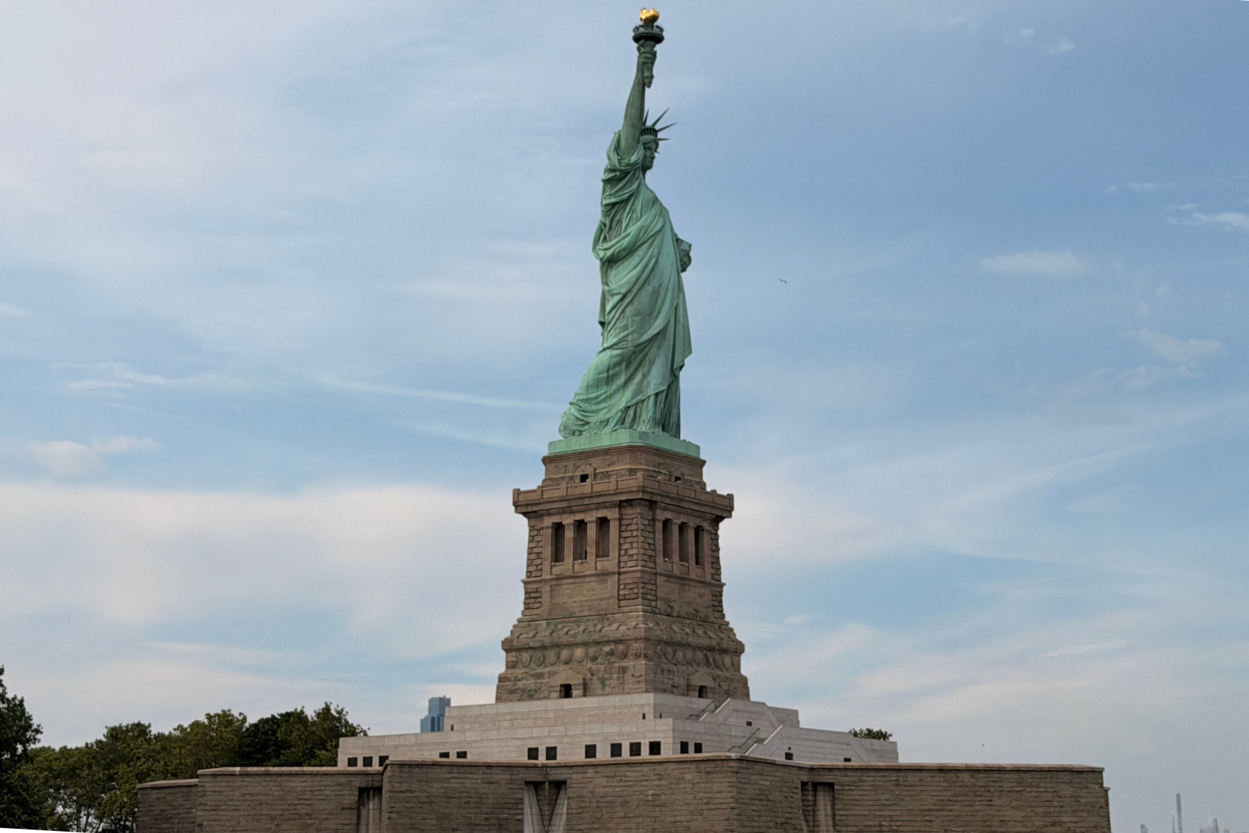 First Time in New York City? Here’s Everything You Need to Know Before You Go! Statue of Liberty standing on its stone pedestal against a blue sky.