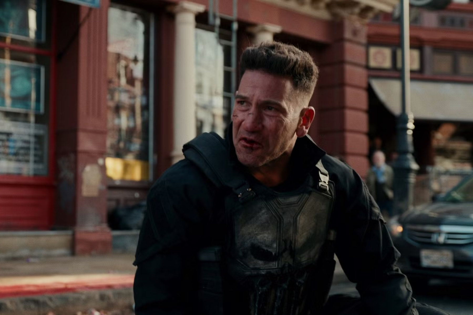 Spider-Man: Brand New Day Review: The Hero Marvel Needed Man in a black tactical suit with a bruised face crouches on a city street, looking tense and alert.