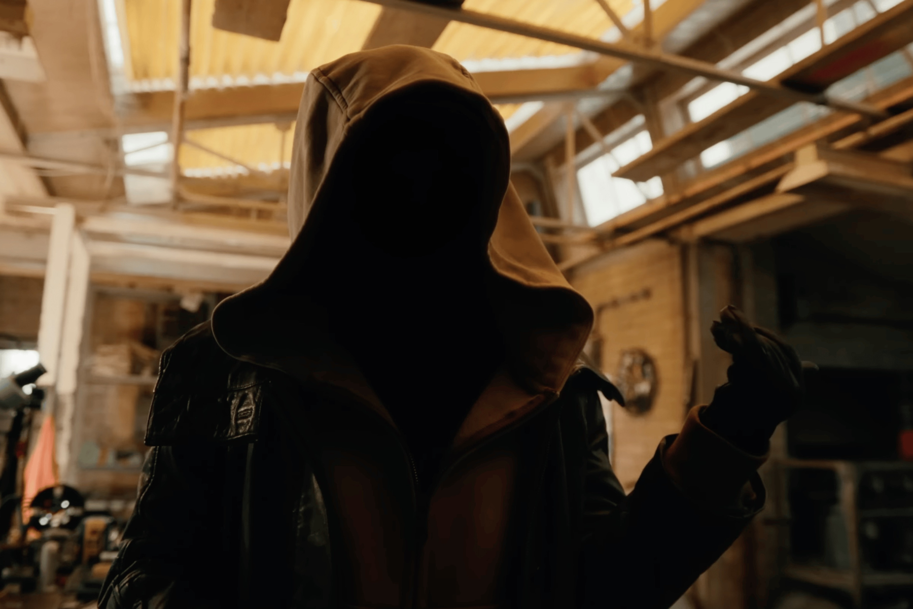 Spider-Man: Brand New Day Review: The Hero Marvel Needed Person wearing a brown hooded jacket in a dim workshop, face obscured by the hood