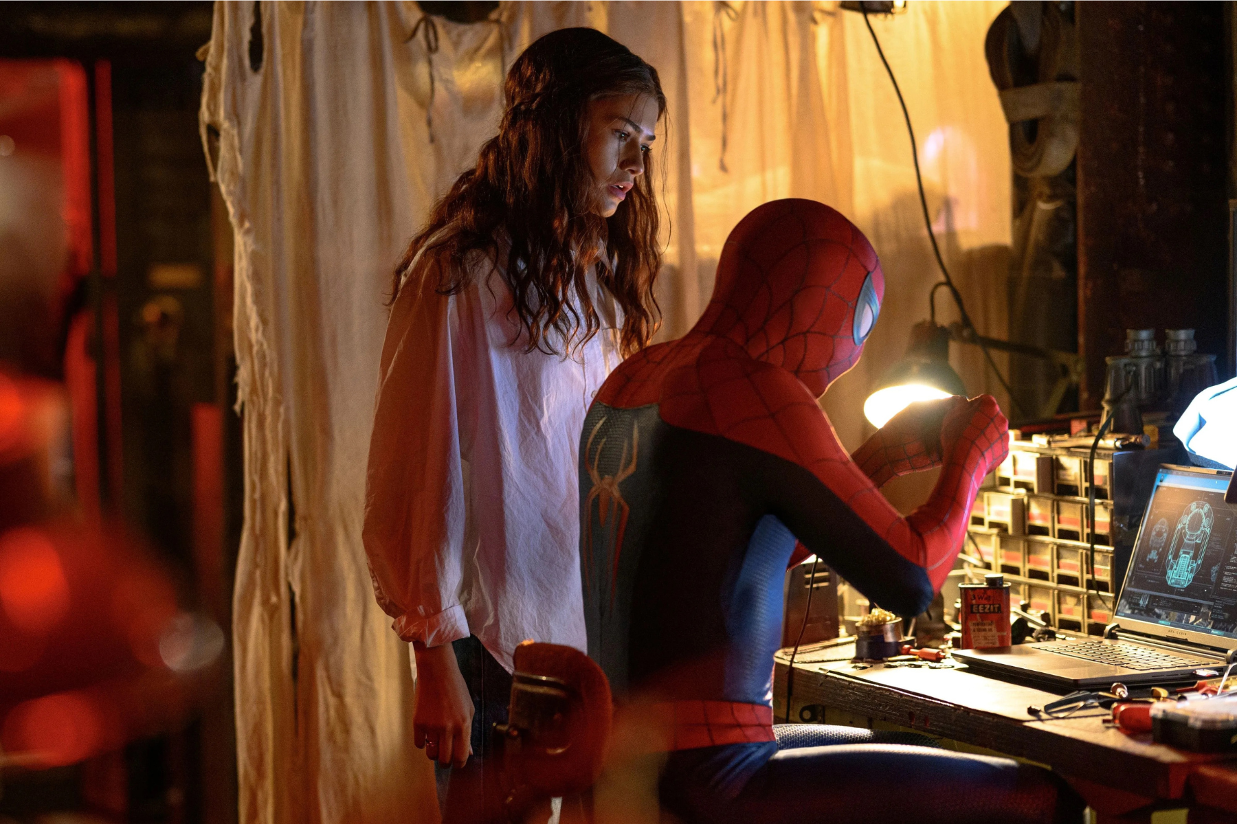 Spider-Man: Brand New Day Review: The Hero Marvel Needed Spider-Man in his red suit consults with a woman in a dim workshop, both looking at a laptop screen with diagrams.