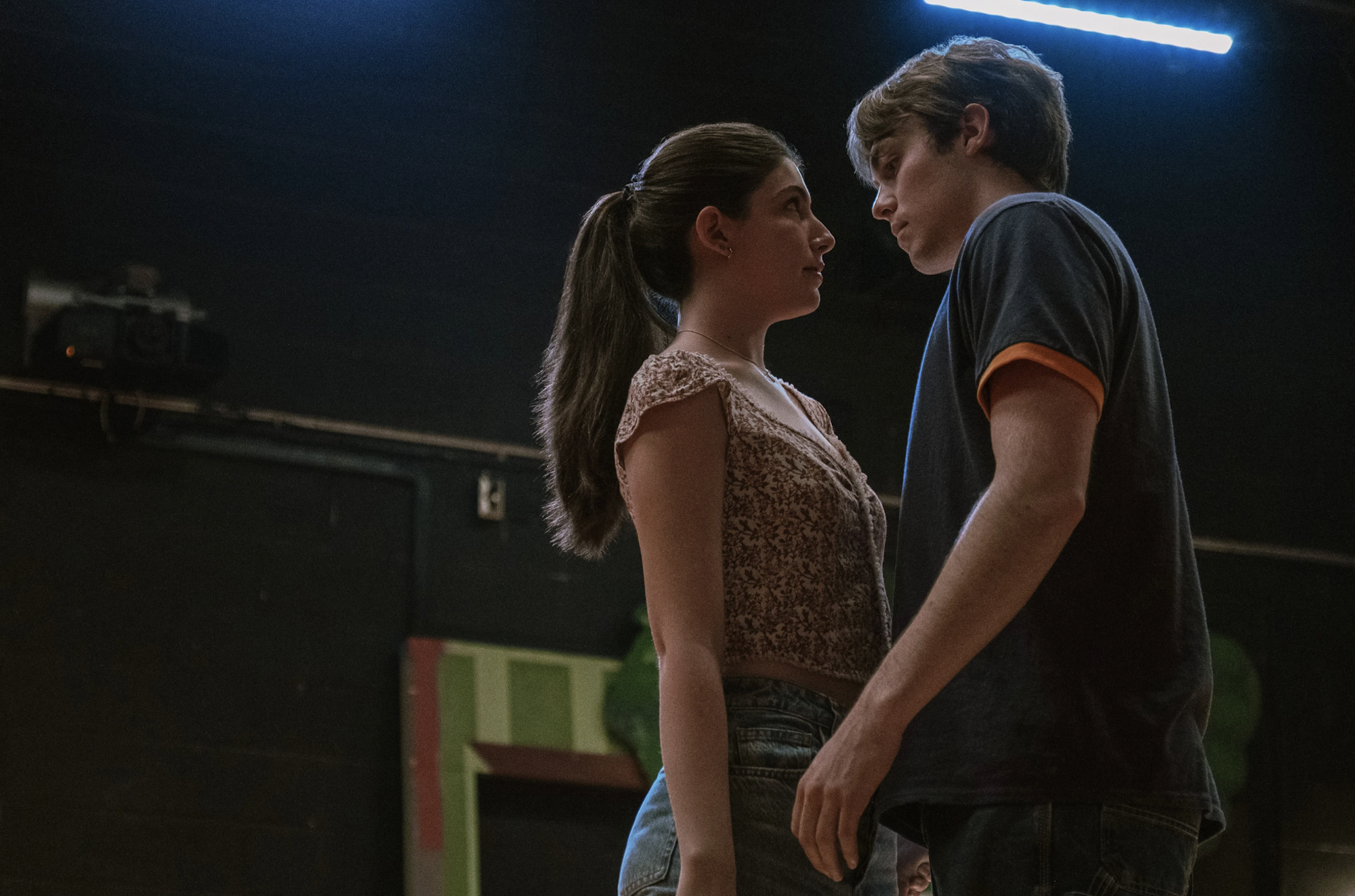 Dont-Say-Good-Luck-2 - Eulalie Magazine Don’t Say Good Luck Review: Sunny Sandler is Solid Gold in This Slice of Life Drama Two people face each other closely in a dim room, holding hands in a quiet moment.