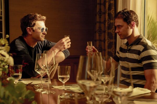Artificial Review: A Scathing Look at OpenAI [NYFF 2026] Two men sitting across from each other toasting - Artificial - film still
