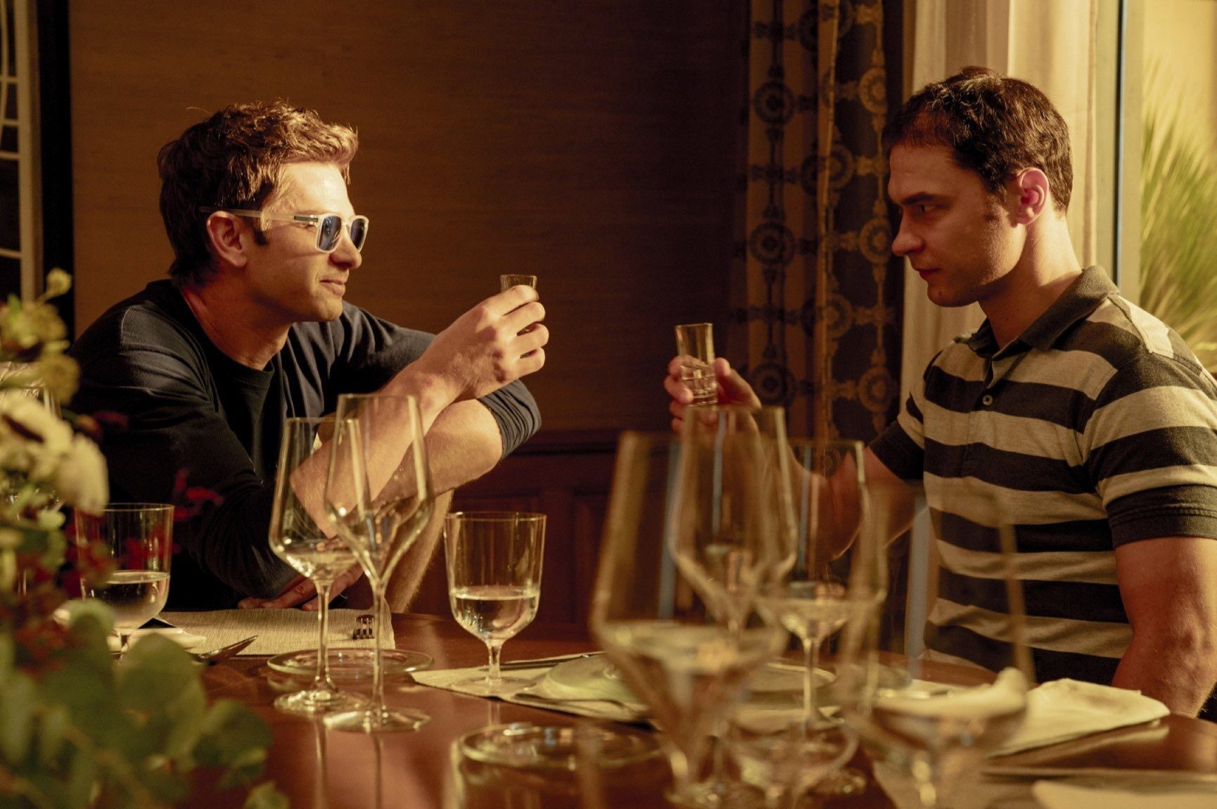 Artificial Review: A Scathing Look at OpenAI [NYFF 2026] Two men sitting across from each other toasting - Artificial - film still
